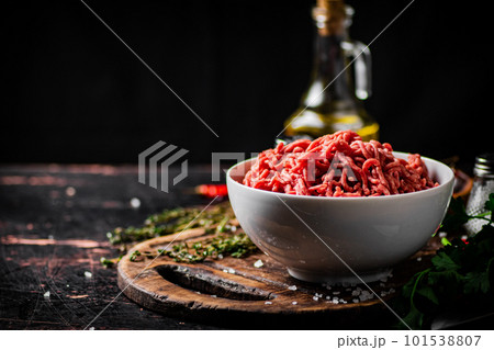 Minced meat in a bowl on a cutting board with sprigs of thyme. 101538807