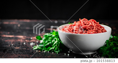 A full bowl of minced meat on the table with parsley. A full bowl of minced meat on the table with parsley. 101538813