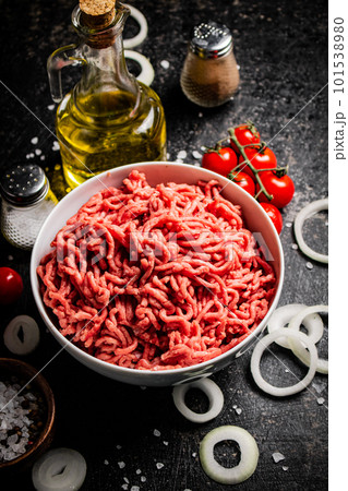 Minced meat in a bowl with onion rings, tomatoes and spices. Minced meat in a bowl with onion rings, tomatoes and spices. 101538980