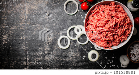 Minced meat in a bowl with onion rings, tomatoes and spices. 101538981