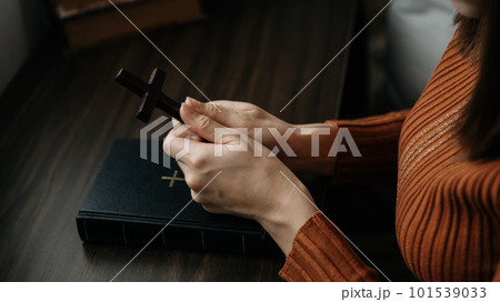Woman sitting and studying the scriptures.The wooden cross in the hands. Christian education concepts The Holy Scriptures open Woman sitting and studying the scriptures.The wooden cross in the hands. Christian education concepts The Holy Scriptures open 101539033