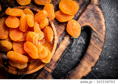 Dried apricots in a plate on a cutting board. 101539703