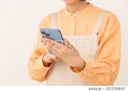 スマホを操作するエプロン姿のシニア主婦 101539843
