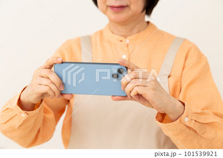 スマホを操作するエプロン姿のシニア主婦 101539921