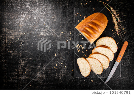 Sliced wheat bread with a knife on a stone board. Sliced wheat bread with a knife on a stone board. 101540791