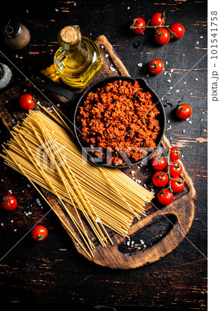 Bolognese sauce on a cutting board with cherry tomatoes and dry pasta. Bolognese sauce on a cutting board with cherry tomatoes and dry pasta. 101541758