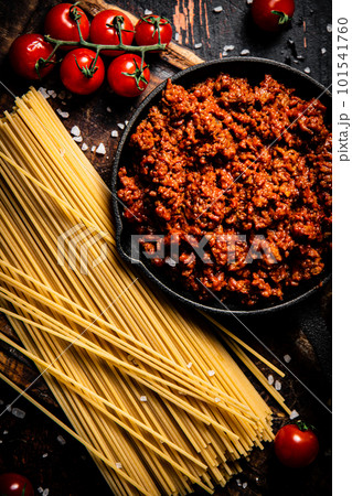 Bolognese sauce on a cutting board with cherry tomatoes and dry pasta. Bolognese sauce on a cutting board with cherry tomatoes and dry pasta. 101541760