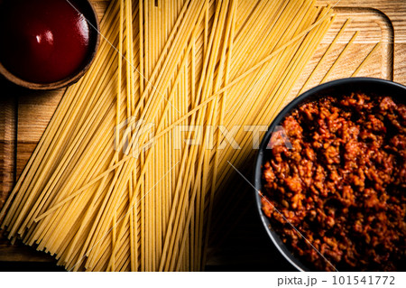 Bolognese sauce with tomato sauce and spaghetti dry on a cutting board. 101541772