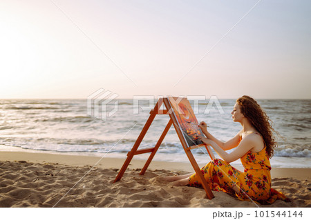 Young female artist drawing the picture at the beach. Hobby and leisure concept Young female artist drawing the picture at the beach. Hobby and leisure concept 101544144