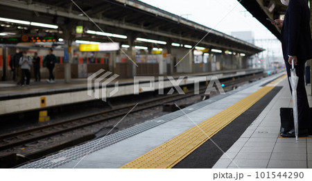 駅のホームでスマホを見るビジネスマンの姿 駅のホームでスマホを見るビジネスマンの姿 101544290