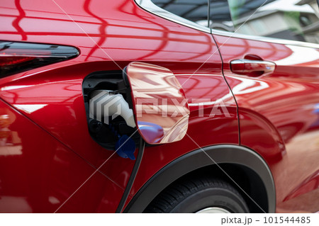 PHEVの赤い自動車に充電しているところ PHEVの赤い自動車に充電しているところ 101544485
