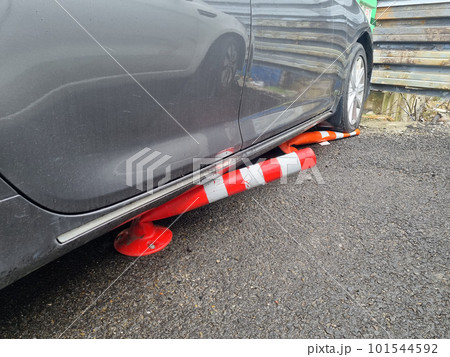 the car is parked with wheels on the barrier cones. 101544592