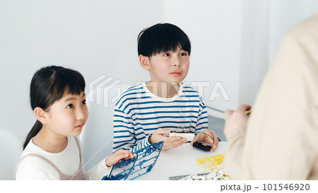 プログラミング教室でロボットの操作を学ぶ女の子と男の子 101546920