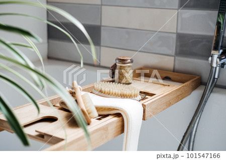 Wooden tray with home spa supplies and bathrobe in modern home bathroom for relaxing rituals. Spa decoration, natural organic products on a bathtube 101547166