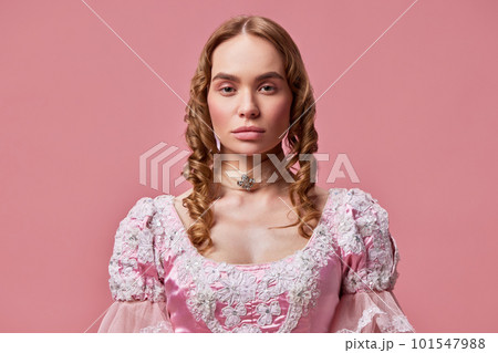 Shot of beautiful princess wearing baroque pink dress and posing over studio background with emotionless face. Medieval evil queen 101547988
