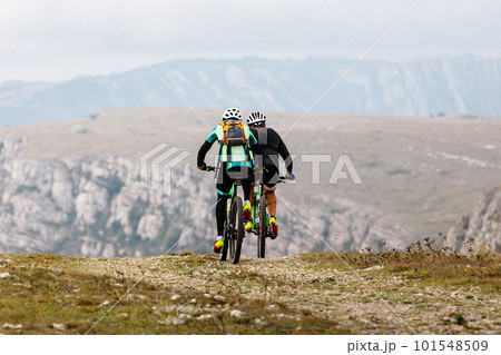 two male cyclist riding mountain cycle on mountainous region travelling cycling. backpack on back of mountain biker 101548509