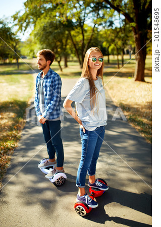 Young man and woman riding on the Hoverboard in the park. content technologies. a new movement. Young man and woman riding on the Hoverboard in the park. content technologies. a new movement. 101548695