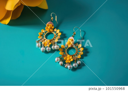 A pair of yellow and white earrings sitting on top of a blue surface. AI generative image A pair of yellow and white earrings sitting on top of a blue surface. AI generative image 101550968