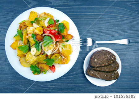 cooked fried omelet with herbs and vegetables in a white plate on a wooden table 101556385