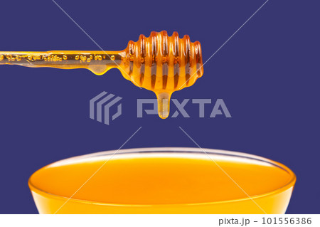 fresh fragrant honey dripping from a spoon into a plate on a blue background 101556386