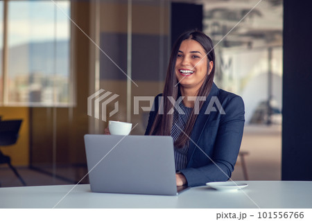 Young woman working on laptop and drinking coffee in office Young woman working on laptop and drinking coffee in office 101556766