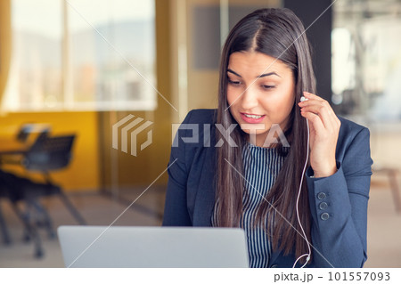 Young Latin Project Manager Putting On Headphones and Working on Laptop Computer in Busy Creative Office Environment. 101557093