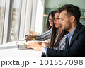 Creative business team sharing laptop in office, watching startup presentation, brainstorming, pointing at monitor, talking. 101557098