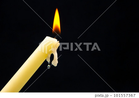 Lighting a candle with a wooden match on a dark background. Burning candle fire 101557367