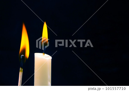 Lighting a candle with a wooden match on a dark background. Burning candle fire 101557710