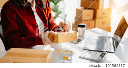 Young woman holding a smartphone showing payment success and credit card with yellow parcel box as online shopping concept 101562317