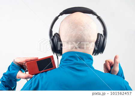 back of the head of a man with headphones in relaxation listening to music on a light background. back of the head of a man with headphones in relaxation listening to music on a light background. 101562457