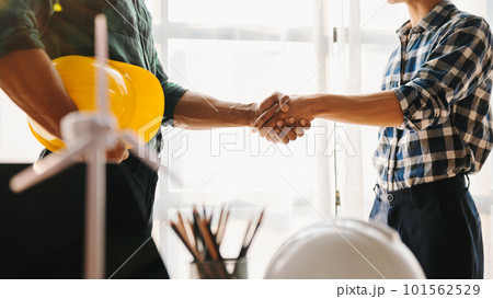 Construction team shake hands greeting start new project plan behind yellow helmet on desk in office to consults about their building project.. Construction team shake hands greeting start new project plan behind yellow helmet on desk in office to consults about their building project.. 101562529