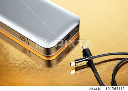 Powerbank portable on a golden background. Electronic devices for charging gadgets and smartphones Powerbank portable on a golden background. Electronic devices for charging gadgets and smartphones 101564115