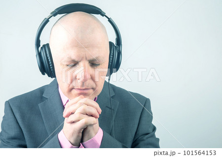 man with closed eyes listens to music with headphones on a light background man with closed eyes listens to music with headphones on a light background 101564153