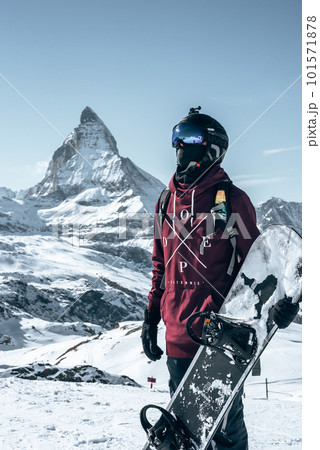 Young snowboarder spending winter holidays in Zermatt, near the famous Matterhorn peak. Male posing in Swiss Alps for the snowboarding season. Young snowboarder spending winter holidays in Zermatt, near the famous Matterhorn peak. Male posing in Swiss Alps for the snowboarding season. 101571878