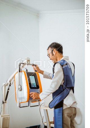 a male vet in x-ray protective apron smiling while operating x-ray machine 101573709