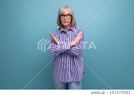 serious 60s middle-aged woman with gray hair in a fashionable shirt on a bright studio background serious 60s middle-aged woman with gray hair in a fashionable shirt on a bright studio background 101575081