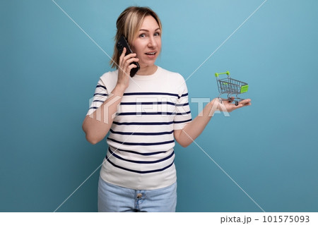 photo for banner woman shopper making order by phone holding shopping trolley on blue background 101575093