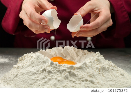 Adding egg to a pile of flour 101575872