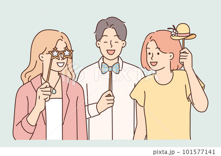Cheerful friends with photo props pose for joint picture during birthday party or holiday festival Cheerful friends with photo props pose for joint picture during birthday party or holiday festival 101577141