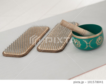 Tibetan singing bowl and sadhu board on yoga mat. 101578041