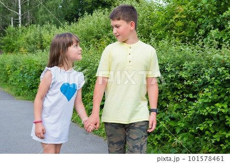 Cute happy kids are walking in the summer park holding hands 101578461