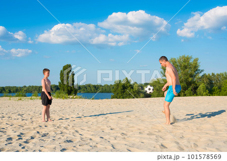 Boy and dad on the beach have fun playing with a ball on vacation. Healthy lifestyle. Boy and dad on the beach have fun playing with a ball on vacation. Healthy lifestyle. 101578569