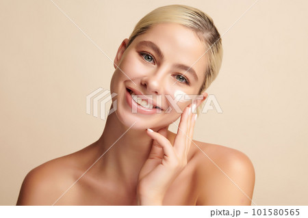 Beautiful young woman applying face cream on beige background, Face care, Facial treatment, Cosmetology, beauty and spa, Asian women portrait. Beautiful young woman applying face cream on beige background, Face care, Facial treatment, Cosmetology, beauty and spa, Asian women portrait. 101580565