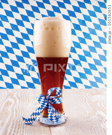 Dark wheat beer in glass on Bavarian pattern background. High quality photo 101582651
