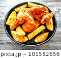 Half chicken roasted with potato wedges on plate, top view 101582656