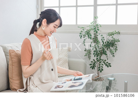 家でコーヒーを飲みながらファッション雑誌・ヘアカタログを見るくつろぐ日本人女性 家でコーヒーを飲みながらファッション雑誌・ヘアカタログを見るくつろぐ日本人女性 101586106