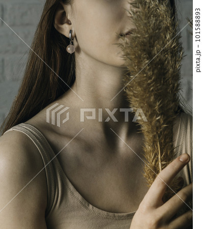 Beautiful earrings with a pink stone and the ears of a girl with a long neck and a bouquet of dried flowers 101588893