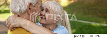 Smiling mature woman with husband in sportswear hug in green park 101589730
