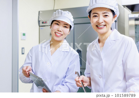 厨房で料理を作る白衣を着た女性調理員 厨房で料理を作る白衣を着た女性調理員 101589789